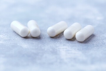 Creatine capsules on bright wooden background. Soft focus. Close up. Copy space.