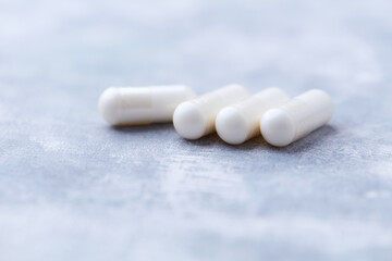 Creatine capsules on bright wooden background. Soft focus. Close up. Copy space.