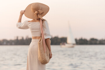 Elegant Woman In Straw Hat Admiring Scenic View By Water At Sunset 