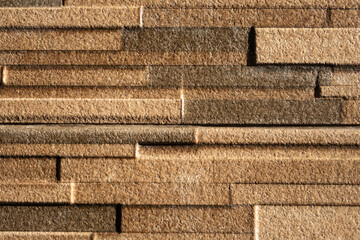 Close-up of a textured stone wall with horizontal layered patterns in warm earthy tones, ideal for...