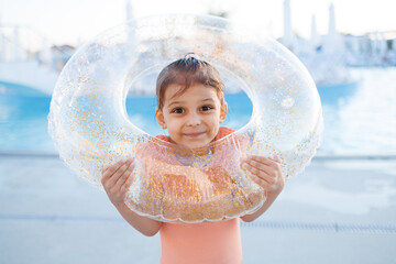 Cute funny toddler girl relaxing on inflatable toy ring floating in pool have fun during summer...