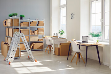 Interior of empty work space with office desk in warehouse with shelves filled cardboard boxes of...