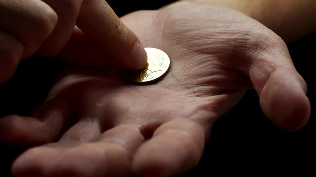 An American cent is in the hands of a guy.
A man holds a metal coin in his hands close-up on a black background.
A man puts a sept. on his hand.
Financial problems and inflation
