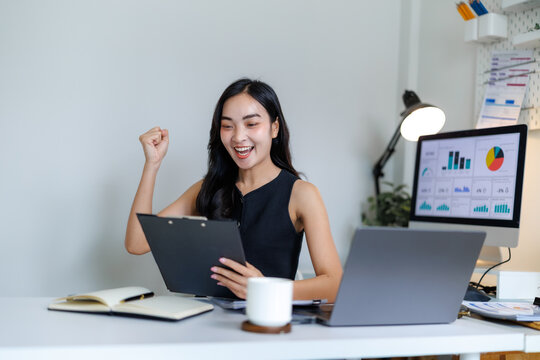 Excited asian businesswoman celebrating business success in modern office