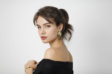 Graceful Woman in Black Off-Shoulder Dress with Gold Jewelry Posing Elegantly 
