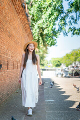 Asian tourist woman walking near Tha Phae Gate in Chiang Mai. Young woman in white dress exploring...