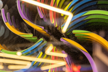 Abstract swirl of colorful neon arcs behind dusty glass, forming a vibrant and dynamic light...