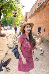 Young Asian woman exploring Tha Phae Gate, a heritage landmark in Chiang Mai, Thailand. Female...