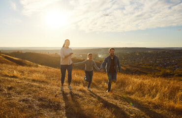 Portrait of happy smiling family with daughter walking outdoors enjoying beautiful nature. Mother,...