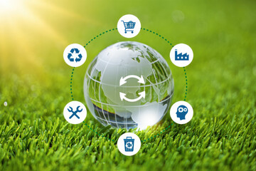 Glass globe on grass with recycling and manufacturing icons connected by dotted lines in a circle