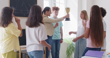 Happy teacher giving school trophy prize award, pleased competition, study winner teen getting team appreciation support applause, children group applauding praising friendship victory success - Powered by Adobe