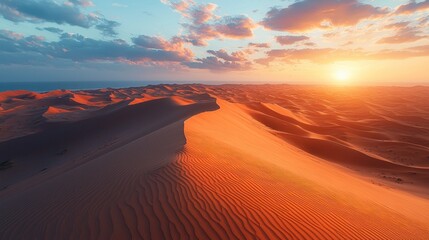 Sunrise over vast desert dunes.  Golden light illuminates the sand