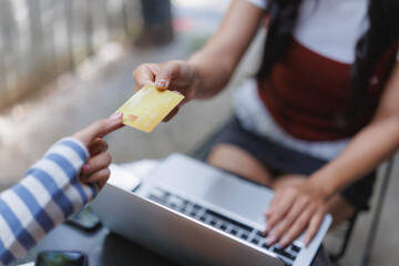 Woman paying with credit card on laptop in outdoor cafe