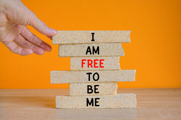 I am free to be me symbol. Concept words I am free to be me on brick blocks on a beautiful wooden table orange background. Businessman hand. Business I am free to be me concept.
