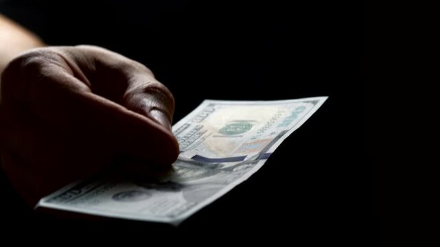 A man gives a bribe on a black background.
Obtaining financial benefits and the problem of corruption.
Bribery and corruption.
Solving problems with money.
Financial fraud and corruption