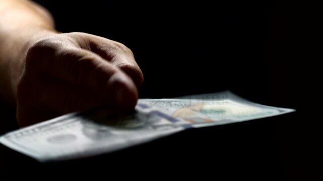 A man gives a bribe on a black background.
Obtaining financial benefits and the problem of corruption.
Bribery and corruption.
Solving problems with money.
Financial fraud and corruption