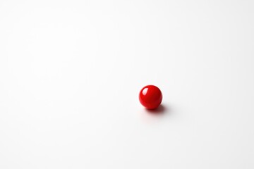 A single red sphere on a clean white surface offers simplicity and minimalist style, ideal for graphic design, product mockup and branding.