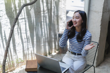 Freelancer woman talking on phone and working on laptop in cafe