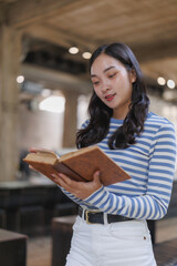 Young woman reading old book in modern library