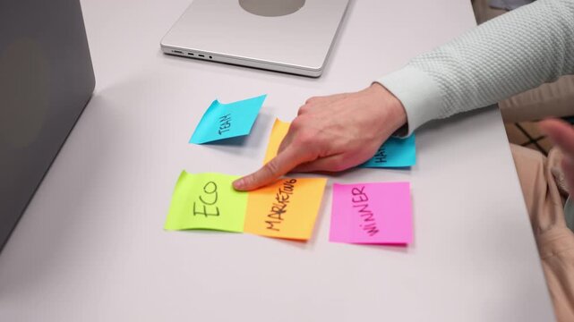 Marketing manager pointing at colorful sticky notes with marketing strategies, focusing on eco friendly approach