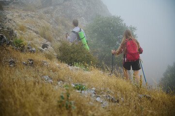 Adventurous Hikers Exploring Misty Hillside With Backpacks and Trekking Gear