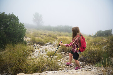 Woman Hiking in Foggy Terrain with Backpack and Trekking Poles