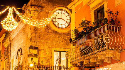 beautiful night view of vintage yellow street building with clock illuminated with holiday decoration