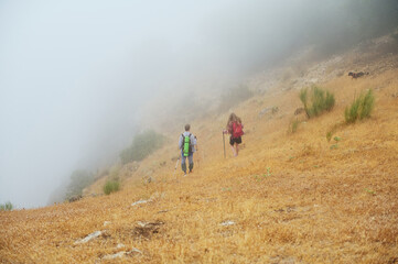 Couple Hiking on a Foggy Mountain Trail Through Dry Grassland and Mist