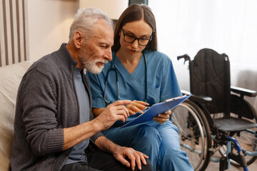 Female doctor showing medical information to senior patient at home