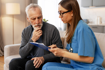Female doctor explaining medical report to senior patient at home