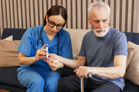 Nurse measuring blood glucose level of senior man using lancet pen - Powered by Adobe