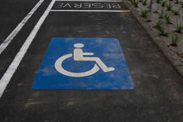 A blue square marked with a white wheelchair symbol and the word “RESERVE” indicates a parking...