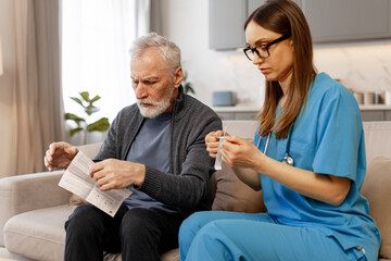 Nurse assisting senior man reading medical instructions at home