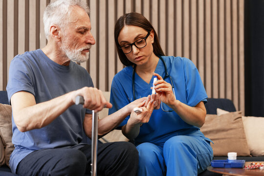 Nurse measuring blood glucose level of senior man using lancet pen - Powered by Adobe