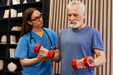 Female doctor assisting senior man lifting weights during rehabilitation session