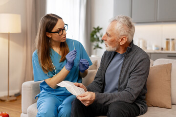 Nurse explaining self-swabbing procedure to senior man at home