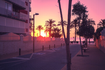A deserted street leading to the embankment in the early morning during sunrise. Avenida de...
