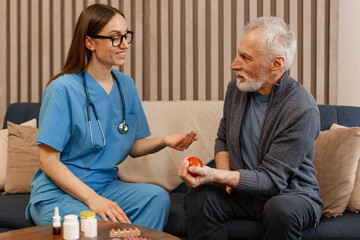 Nurse assisting elderly man with hand exercises and medication at home