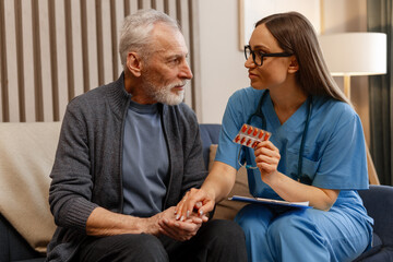 Smiling doctor comforting senior man and explaining medicine dosage at home visit