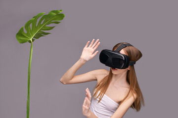 Young caucasian female engaging with virtual reality while interacting with a tropical leaf.
