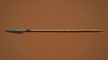 Presenting handcrafted spear resting on solid brown backdrop, with leaf-shaped stone tip