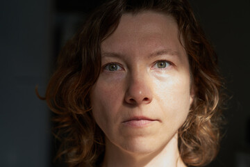 Caucasian female adult with wavy hair in natural light shadowed portrait.