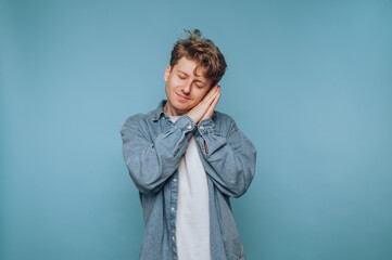 Young man expresses happiness with a playful gesture against a solid blue background in a cheerful...