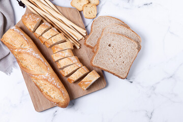Assortment of Bread Products on white marble background. Top view. Copy space