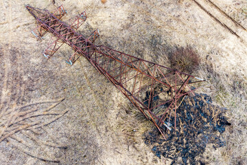 Aerial view of a rusty transmission line support overturned on the ground, dismantling of an obsolete metal structure