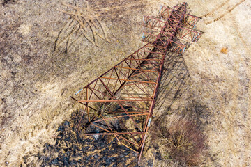 Aerial view of a rusty transmission line support overturned on the ground, dismantling of an obsolete metal structure