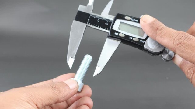Hand measure diameter hex bolt using digital vernier caliper on black background. Universal tool for high-precision measurements of external and internal dimensions. Measurement tool.