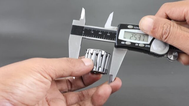 Hand measure diameter roller bearing using digital vernier caliper on black background. Universal tool for high-precision measurements of external and internal dimensions. Measurement tool.