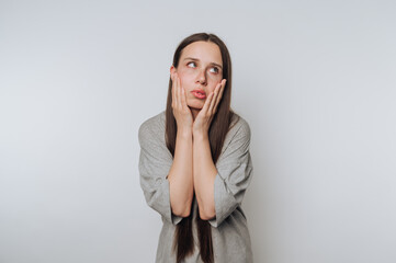 Young woman shows expression of frustration in neutral setting with long hair and casual clothing