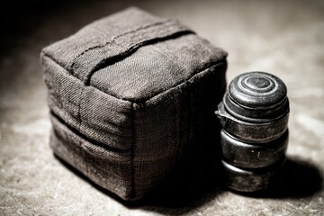 Dark, still life of a  heavy canvas cube with metal discs